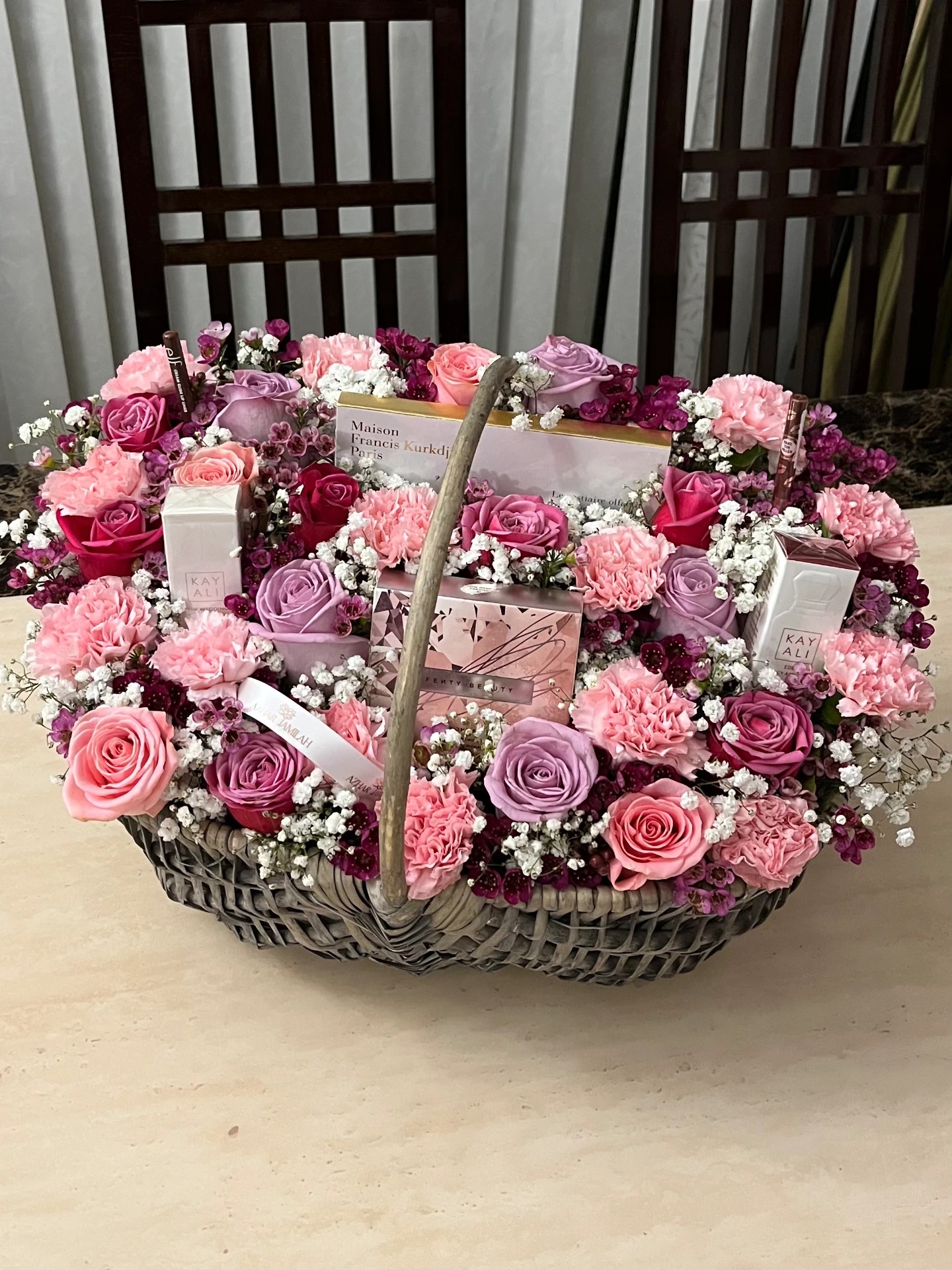 A pastel rose, carnation and wax flower basket arranged with designer fragrance gifts and a personalised ribbon.