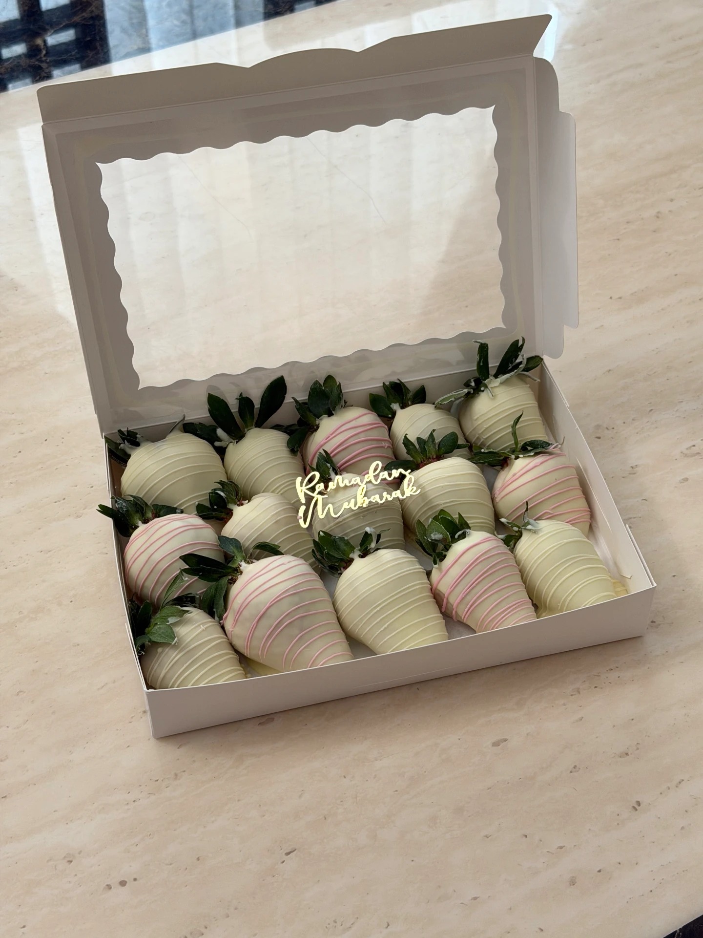 A box of white chocolate strawberries with pink drizzle and a gold Ramadan Mubarak topper.